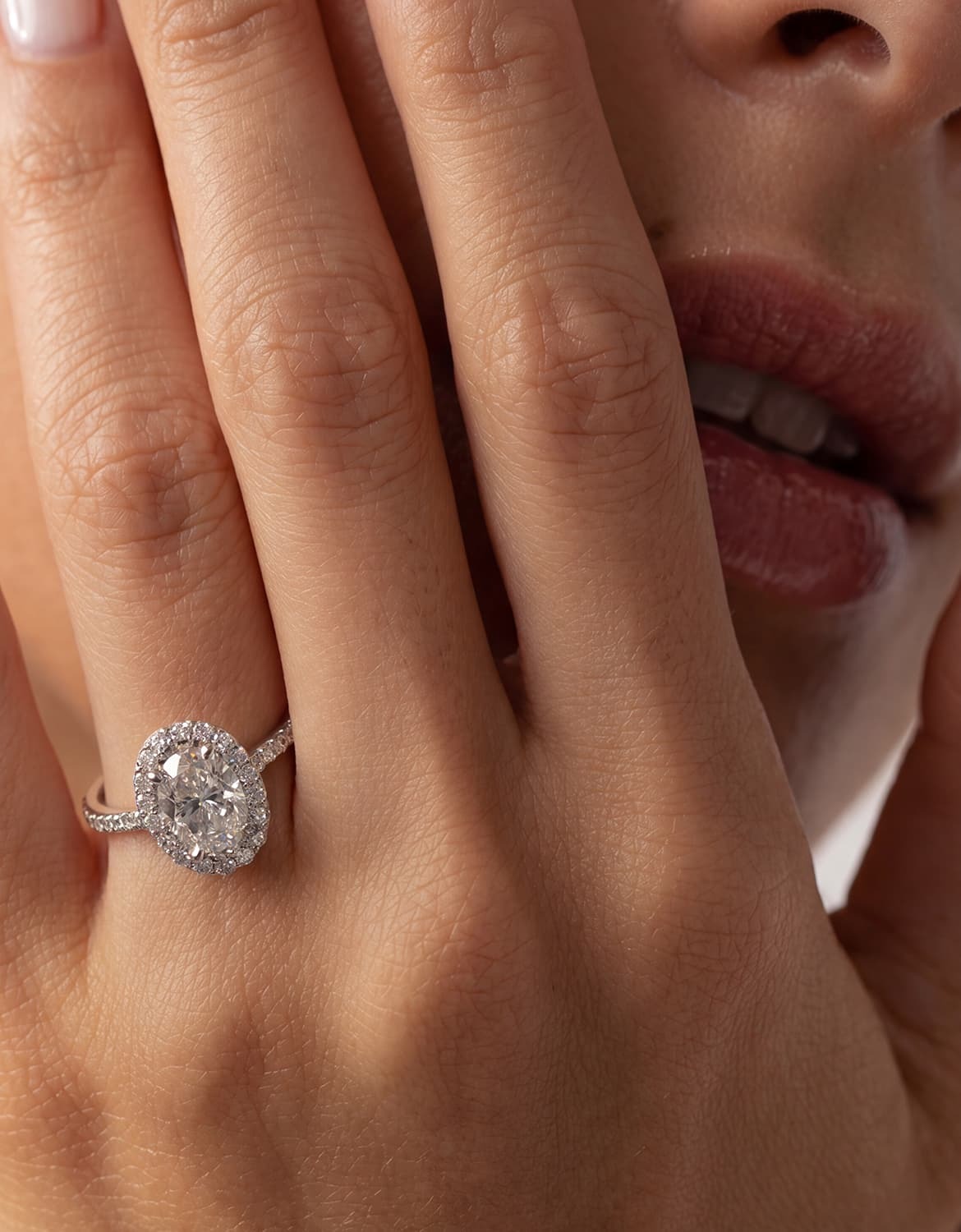 Custom engagement ring design with an oval halo diamond ring worn on hand